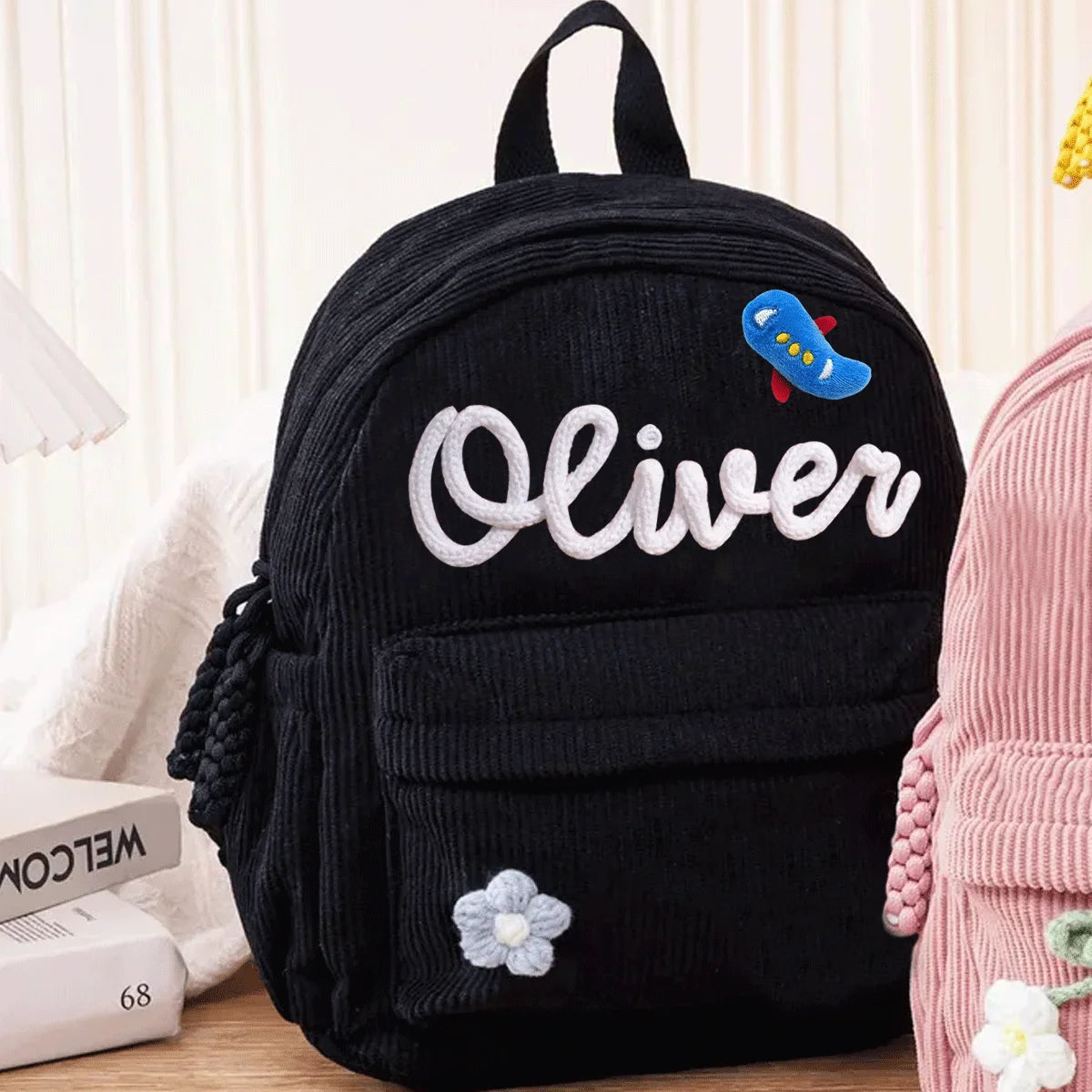 Schwarzer Cordhosenrucksack mit dem Namen Oliver und einem kleinen blauen Anhänger