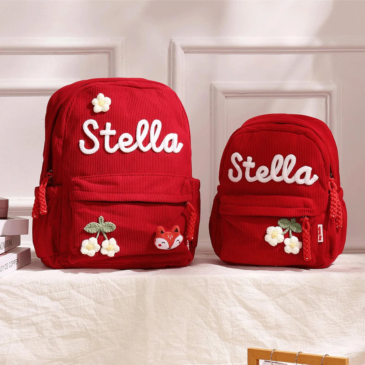 Rote Cordhosen-Rucksack mit der Aufschrift Stella und floralen Designs