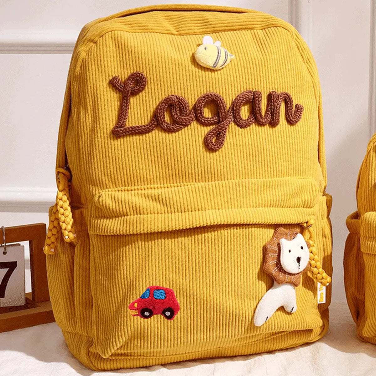 Gelischer Cordhosenrucksack mit dem Namen Logan und einem Bienencharm