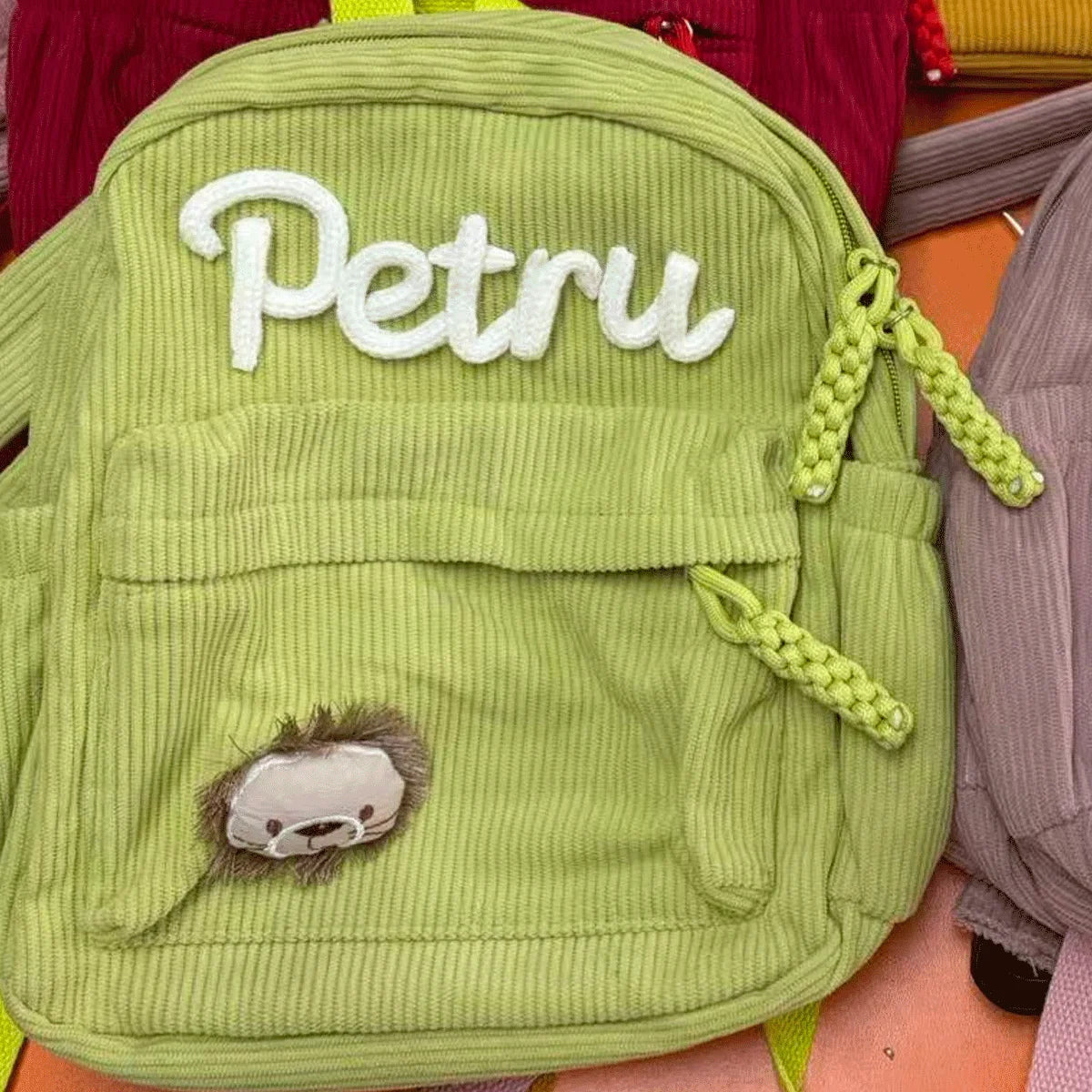 Hellgrüner Samtrucksack mit dem Namen Petru und einem kleinen pelzigen Aufnäher.