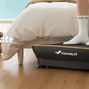 Una persona de pie en una plataforma vibratoria negra para fitness de cuerpo completo en un dormitorio.