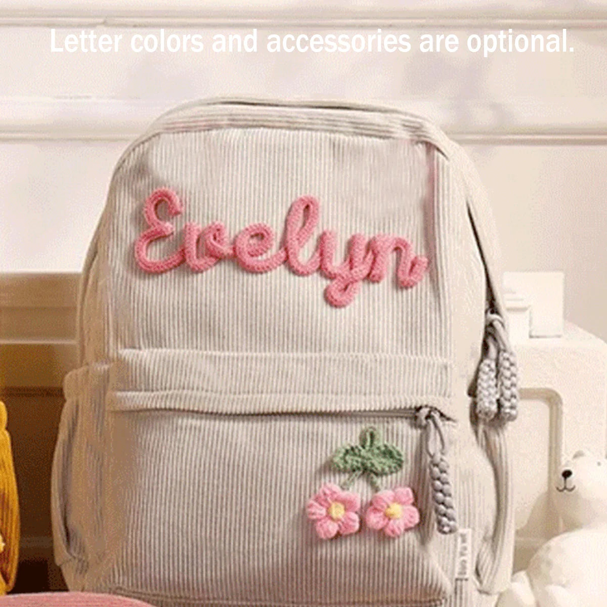 Helles beige Cordhosen-Rucksack mit rosa besticktem Namen Evelyn und Blumenaccessoires.