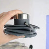 A hand holds a black silicone collapsible travel water bottle with a silver cap.