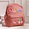Rosa Corduroy Rucksack mit dem Namen Quinn in farbiger Fadenstickerei.