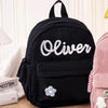 Schwarzer Cordhosenrucksack mit weiß besticktem Namen Oliver und kleinem Blumen-Detail
