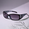 Gafas negras con estampado Y2K blanco en marco cuadrado sobre una superficie clara.