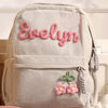 Helles beige Samtfell-Rucksack mit dem Namen Evelyn in rosa Garn und kleinen Blumenverzierung