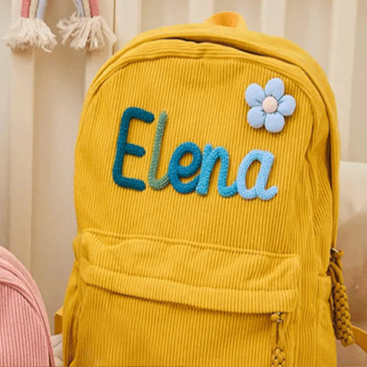 Gelischer Cordhosen-Rucksack mit dem Namen Elena in blauer Fadenstickerei.