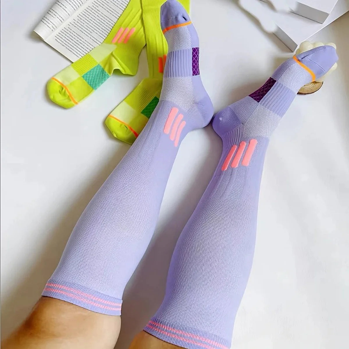Purple graduated compression knee high socks with pink accents and a yellow pair in the background