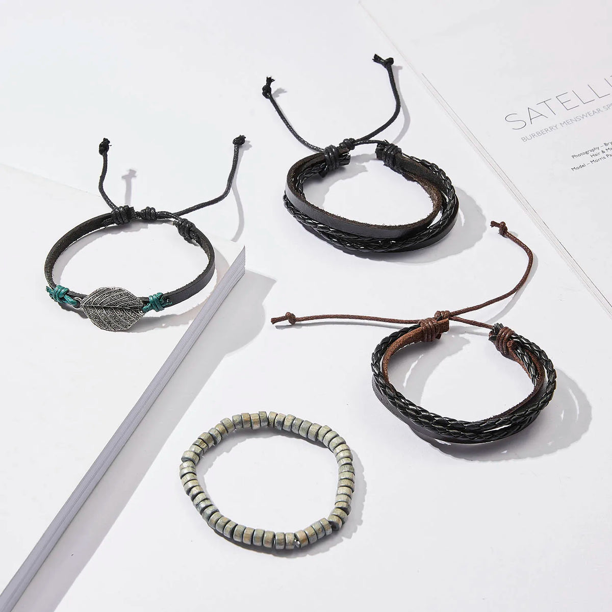 Eine Sammlung handgefertigter Lederblatt-Feder-Armbänder in verschiedenen Stilen und Farben auf einer weißen Oberfläche.
