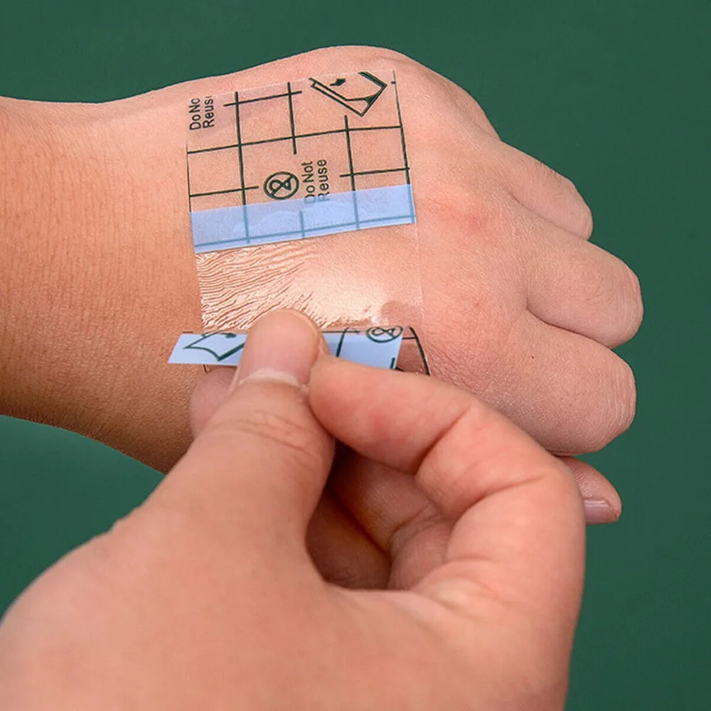 A hand is holding a waterproof film dressing for tattoo aftercare placed on the skin.