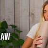 A blonde woman holds a beige insulated water bottle with a flip straw against a wooden background.