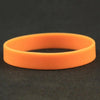 An orange silicone elastic wristband lying on a dark surface.