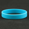 A bright blue silicone elastic wristband lying on a dark surface.