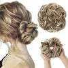 A woman's hair styled in a loose, textured bun with blonde highlights and extensions.