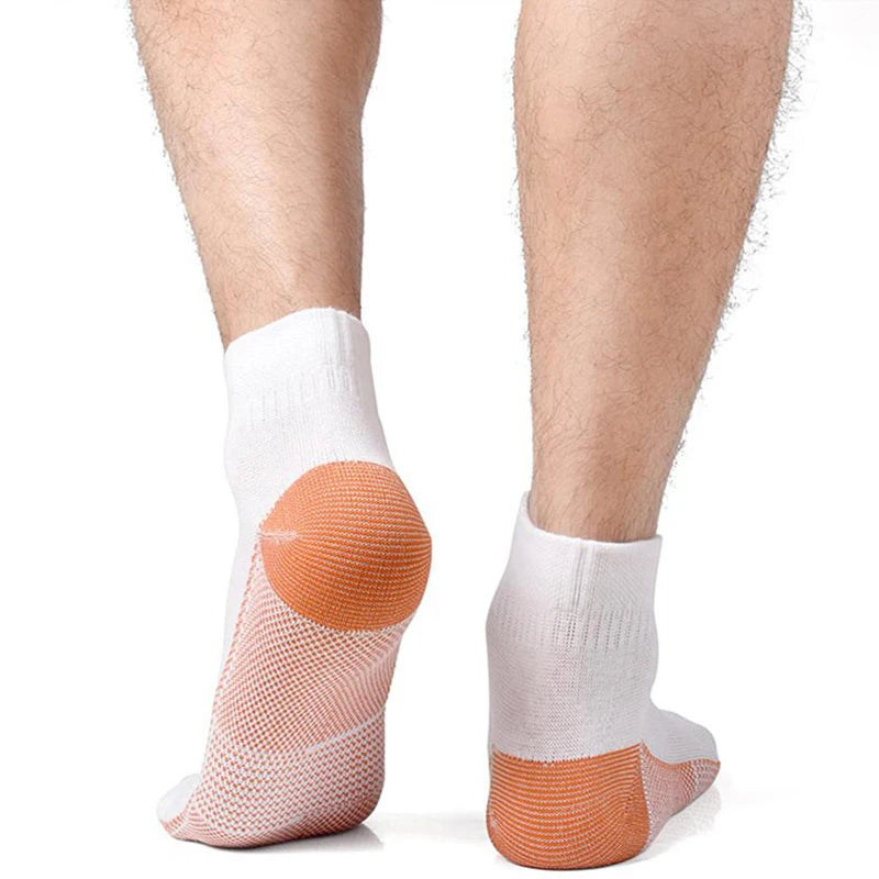Une paire de chaussettes de compression en fibre de cuivre sur un pied, montrant la semelle orange et le tissu blanc.