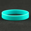 A bright cyan silicone elastic wristband lying on a dark surface.