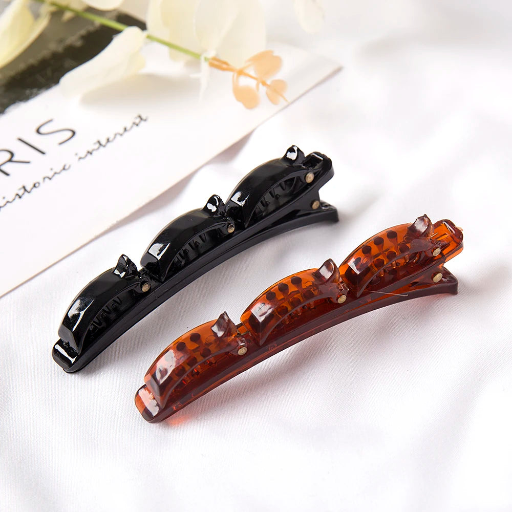 A close-up of a black and amber rhinestone headband resting on white fabric.