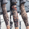 A close-up of a person wearing dark gray reusable UV protection tattoo arm sleeves featuring intricate black and orange triba