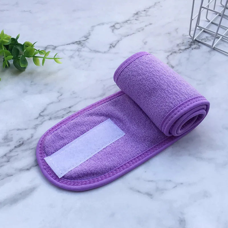 A purple absorbent cloth towel rolled up and placed on a white marble surface.