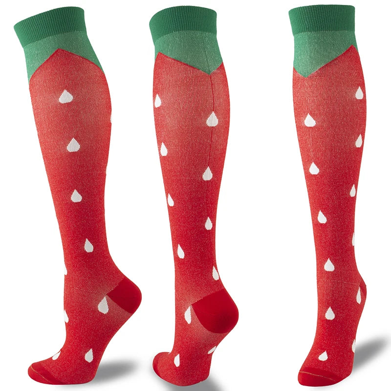 A pair of red compression socks with green cuffs and white polka dots shown from the side.