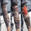 A person wearing dark patterned tattoo arm sleeves on their forearm, displayed against a light background.