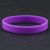 A purple silicone elastic wristband lying on a dark surface.