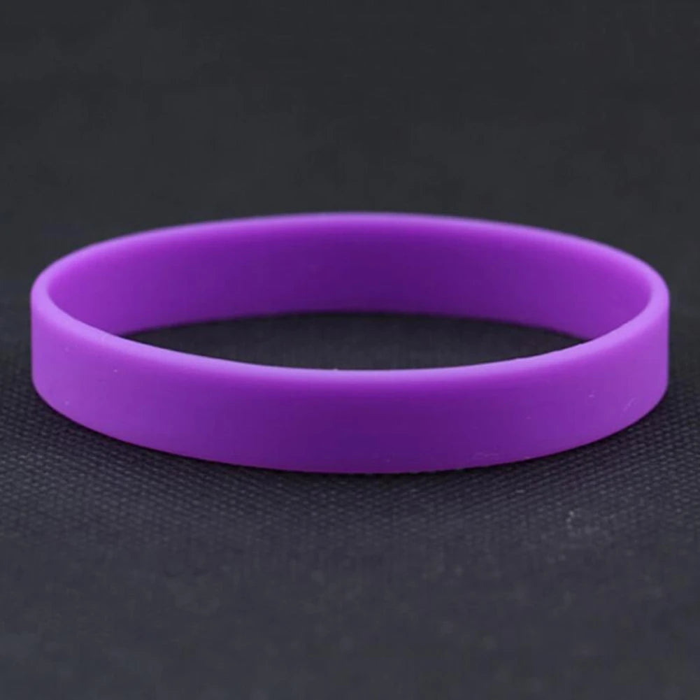 A purple silicone elastic wristband lying on a dark surface.