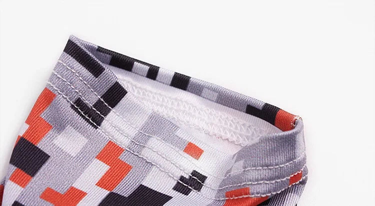 Close-up of a tactical arm sleeve fabric featuring a gray and black geometric pattern with orange accents.