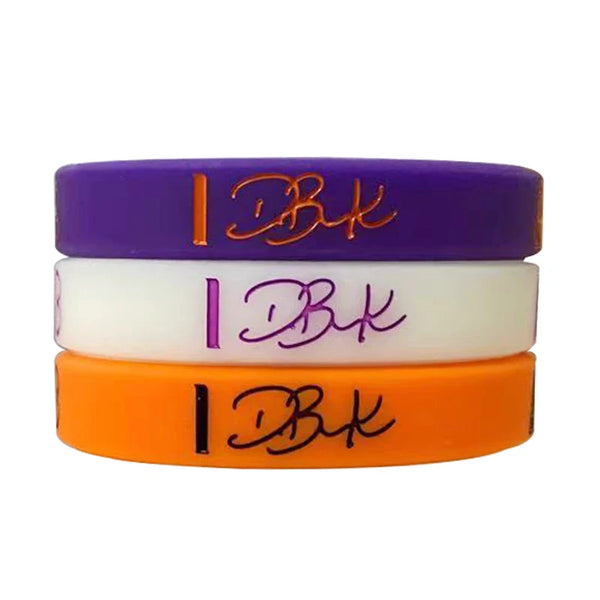 Three silicone wristbands in purple, white, and orange with the initials DBK engraved on them