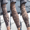 Close-up of a person wearing dark patterned tattoo arm sleeves on their forearm.