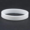 A white silicone elastic wristband lying on a dark surface.