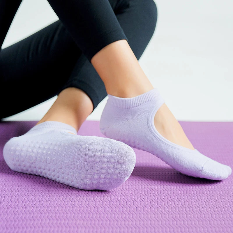 A pair of light purple breathable women's pilates and yoga socks resting on a purple mat.