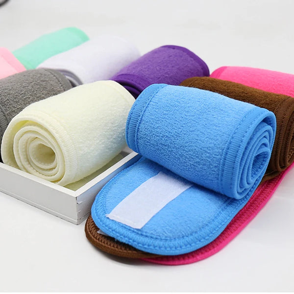 Une collection de serviettes absorbantes colorées roulées et un bandeau bleu sont exposés sur une surface blanche.