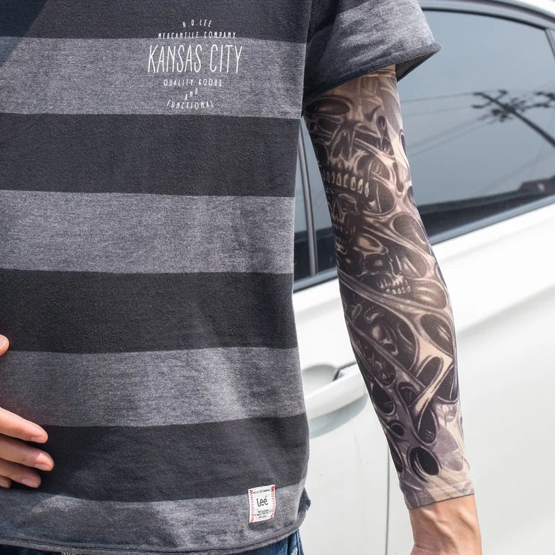 A person wearing a gray striped t-shirt displays a full sleeve tattoo on their arm.