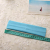 A light blue elastic headband is shown next to a ruler on a white textured surface.