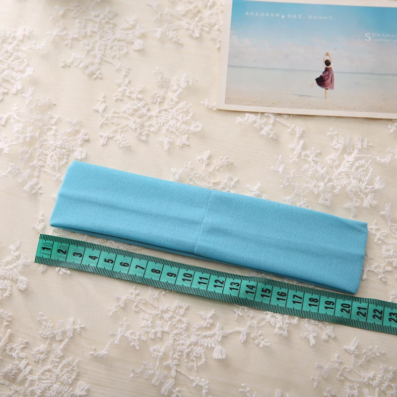 A light blue elastic headband is shown next to a ruler on a white textured surface.