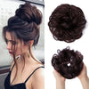 A woman shows off messy curly hair bun extensions styled in an updo and loose curls.