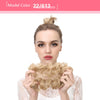 A woman shows off messy curly hair bun extensions with light blonde hair against a white background.