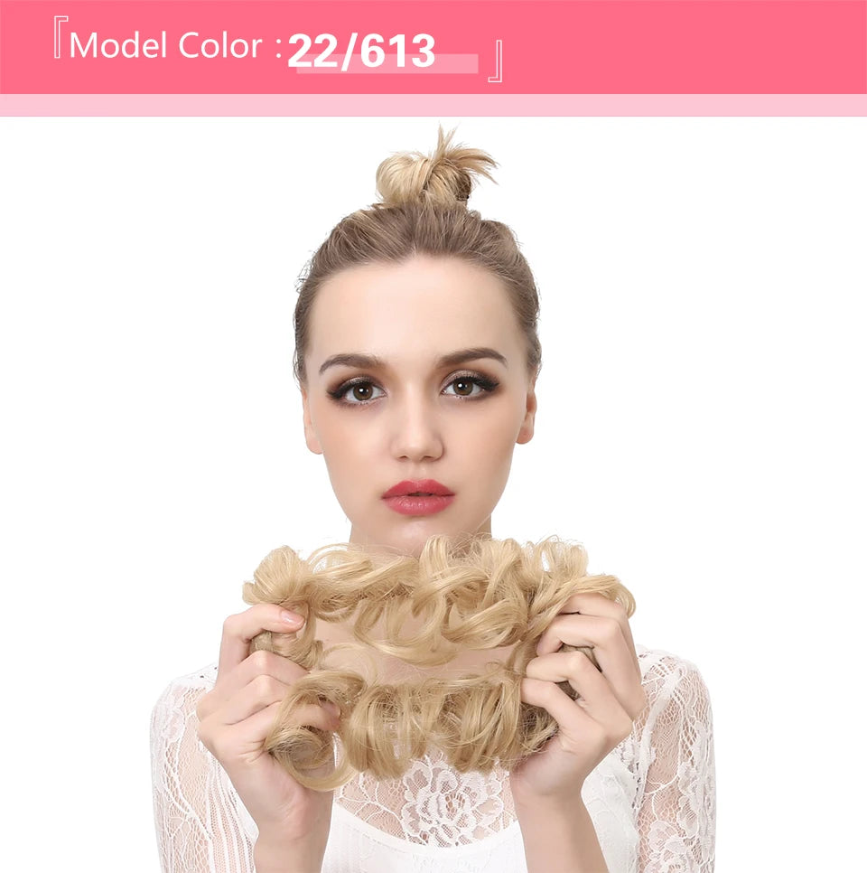 A woman shows off messy curly hair bun extensions with light blonde hair against a white background.