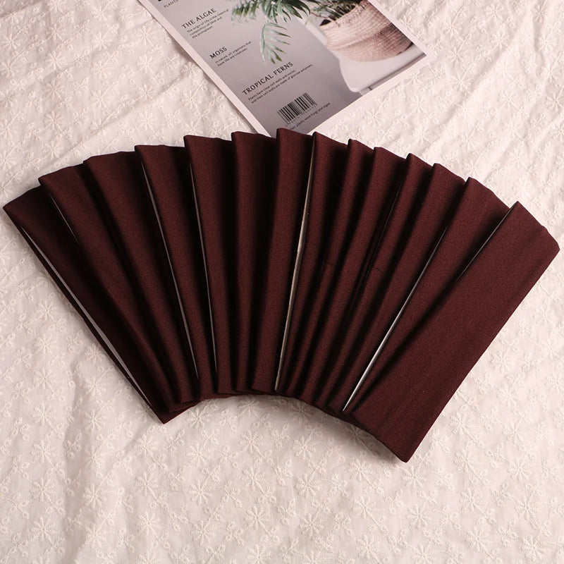A fan of dark brown elastic headbands for sports and hair displayed on a white surface.