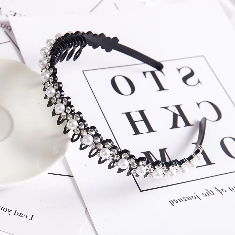 A black headband featuring a double layer design of pearls and rhinestones on a white background.