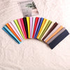A collection of multi-use elastic headbands in various colors and shades laid out on a light fabric.