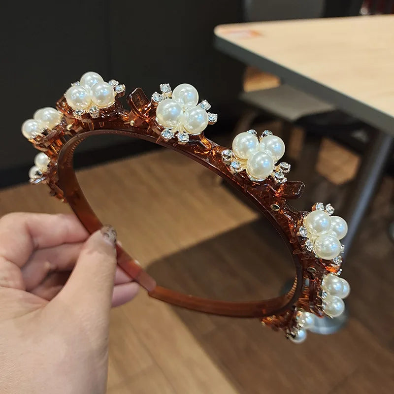 A close-up of a brown headband decorated with white pearls and clear rhinestones.