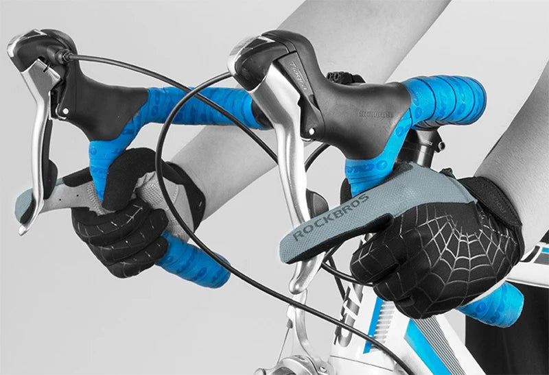 Close-up of hands wearing black cycling gloves and blue riding gloves gripping a bicycle handlebar.