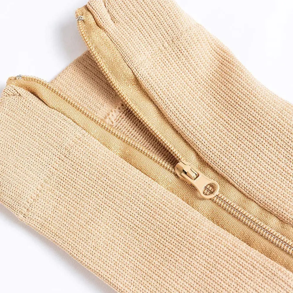 Close-up of beige zipper compression socks showing the fabric texture and metallic zipper detail.