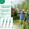 A man shoots an arrow with lighted nocks in an outdoor setting, demonstrating archery equipment.