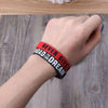 A hand wearing a red silicone elastic bracelet with the text NEVER GIVE UP THE DREAM on it.