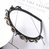 A black headband decorated with gold-toned metalwork and sparkling pearl and rhinestone accents.