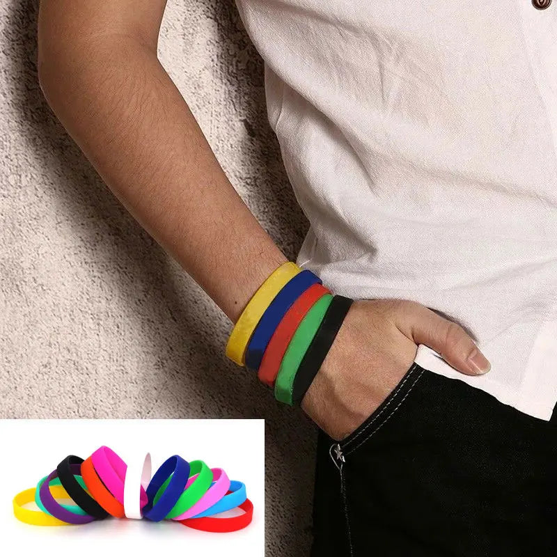 A hand wearing a stack of multi-colored silicone elastic wristbands against a neutral background.
